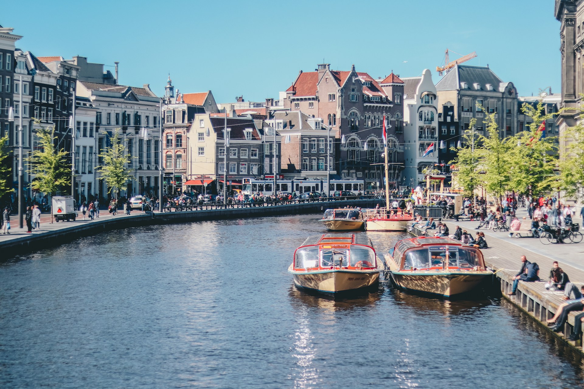 Amsterdam, Netherlands (Photo by <a href="https://unsplash.com/@ethanhjy?utm_content=creditCopyText&utm_medium=referral&utm_source=unsplash">Ethan Hu</a> on <a href="https://unsplash.com/photos/boats-on-the-river-near-the-building-gP2PNn1fCiU?utm_content=creditCopyText&utm_medium=referral&utm_source=unsplash">Unsplash</a>)